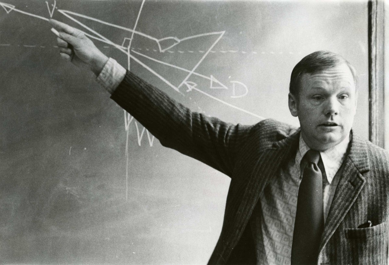 Neil Armstrong lectures with diagrams on a chalkboard