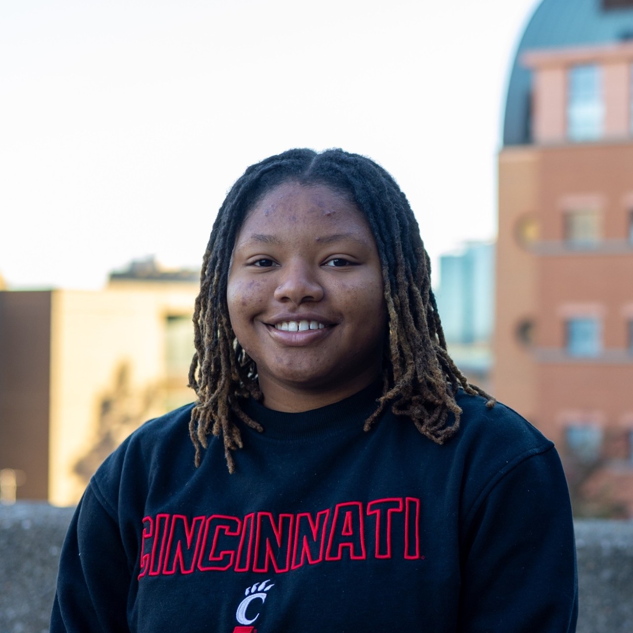student stands in front of campus