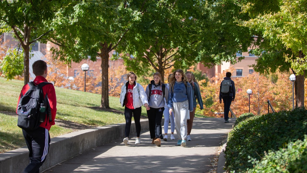 students walking across college campus on a path surrounded by trees