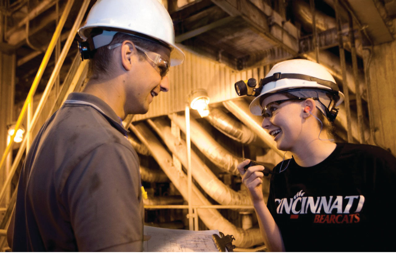 two students wearing hard hats on a construction site