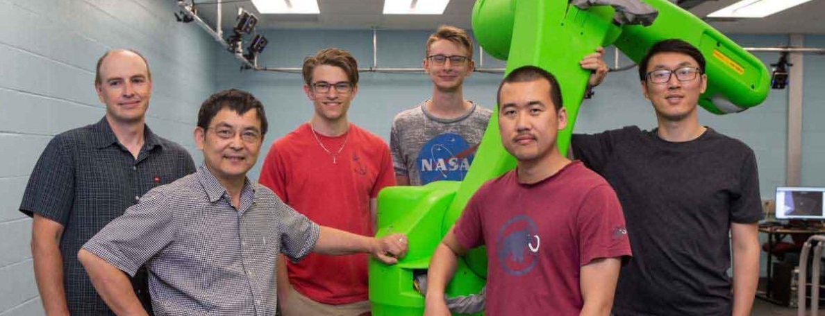 Group of six people in front of a robot