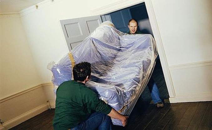 Two people carrying a couch
